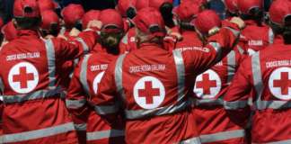 foto da dietro di un gruppo di persona con indosso una giacca della croce rossa italiana